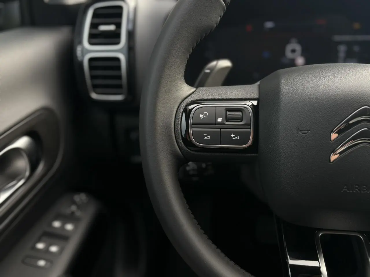 Gros plan sur le volant cuir noir du Citroën C5 Aircross 2025 avec commandes intégrées côté gauche.