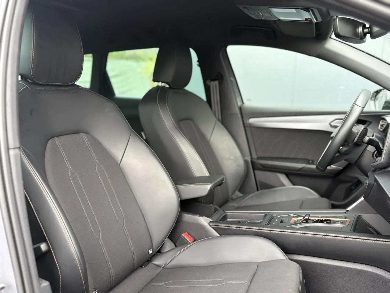 Vue intérieure côté conducteur de la CUPRA LEON ST 2025, sièges cuir noir avec surpiqûres contrastées et console centrale.