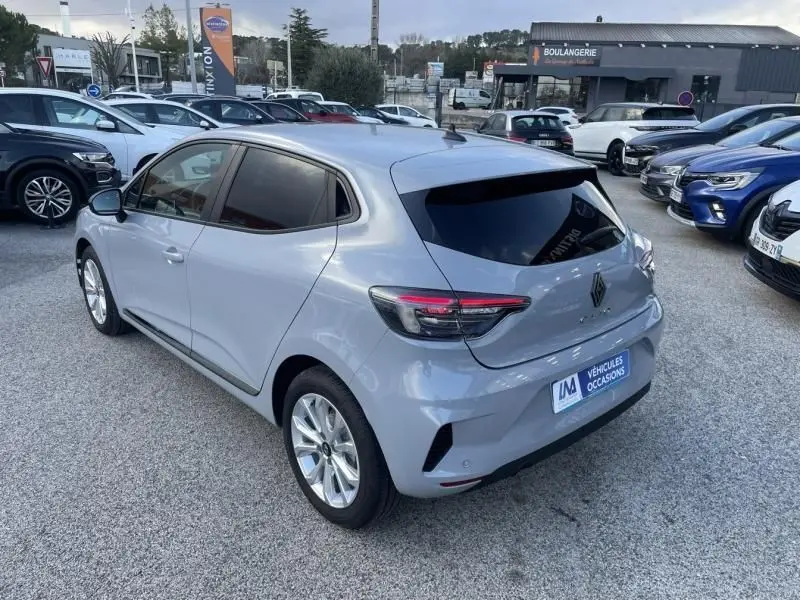 Vue 3/4 arrière droite d'une Renault Clio V gris métal 2025, version DCI 100 Evolution, stationnée en extérieur.