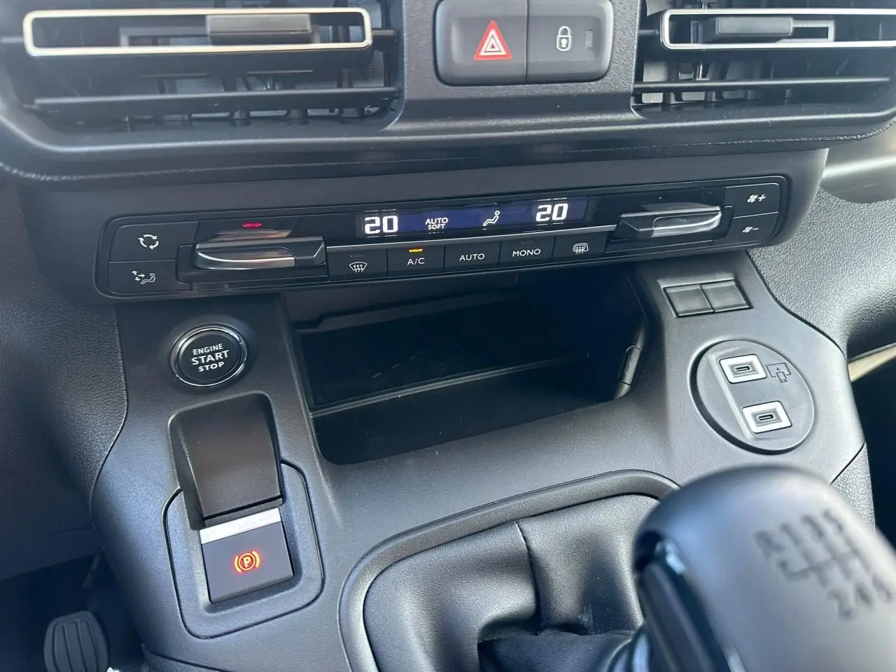 Vue rapprochée de la console centrale noire du Citroën Berlingo blanc, avec commandes climatisation et bouton start/stop.