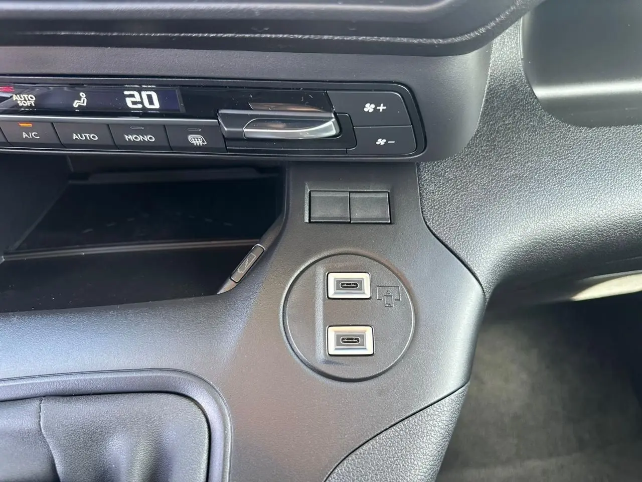 Vue rapprochée du tableau de bord noir du Citroën Berlingo 2026, montrant les commandes de climatisation et deux ports USB-C.