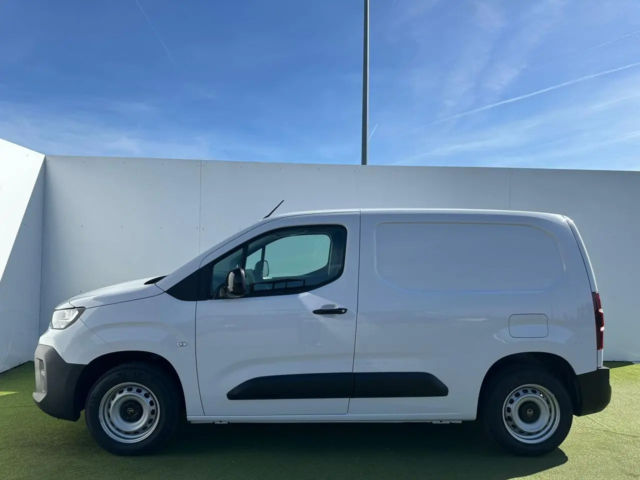 Profil côté gauche d’un utilitaire Citroën Berlingo blanc Icy avec jantes tôles grises et poignées noires.