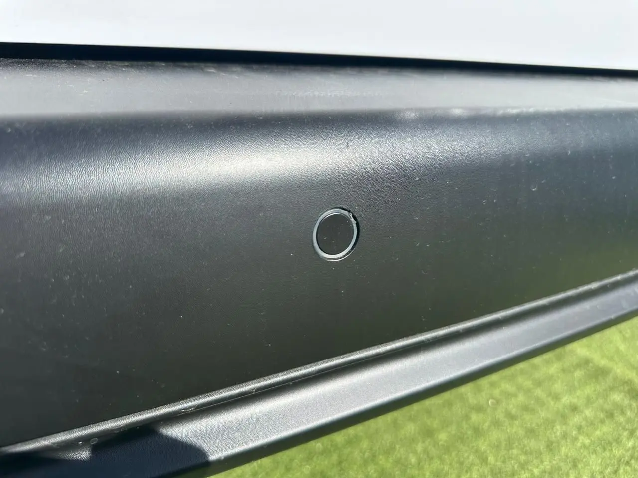 Gros plan sur le capteur de stationnement arrière noir du Citroën Berlingo blanc Icy, vue latérale basse.