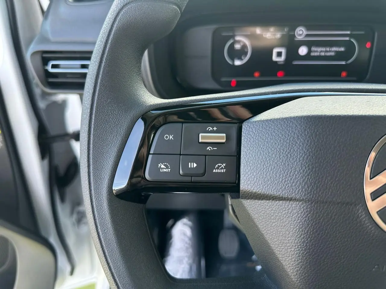 Gros plan sur les commandes au volant côté gauche du Citroën Berlingo blanc, avec tableau de bord numérique en arrière-plan.