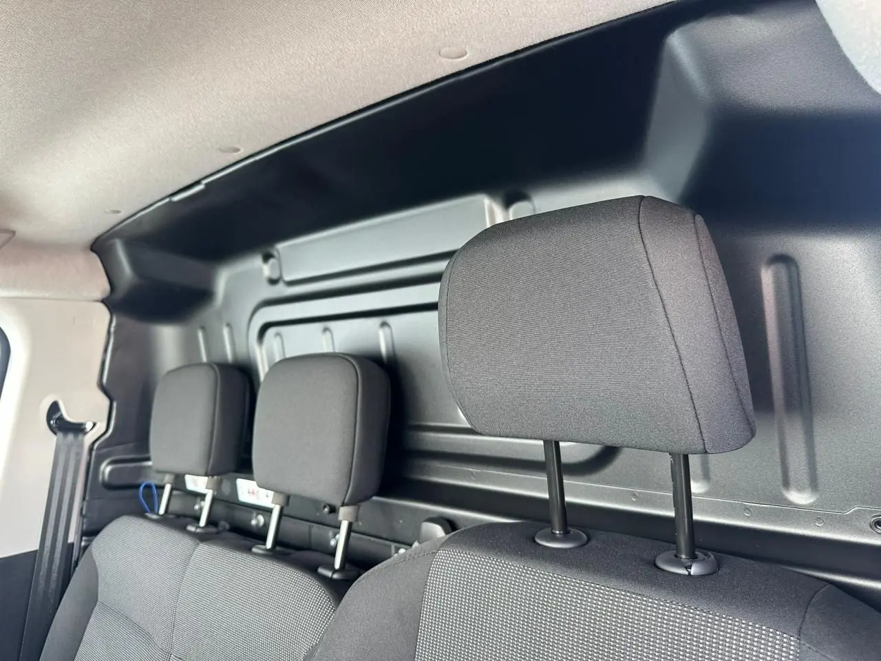 Vue intérieure sur la banquette passager noire avec appuis-tête, cloison métallique arrière du Citroën Berlingo blanc.