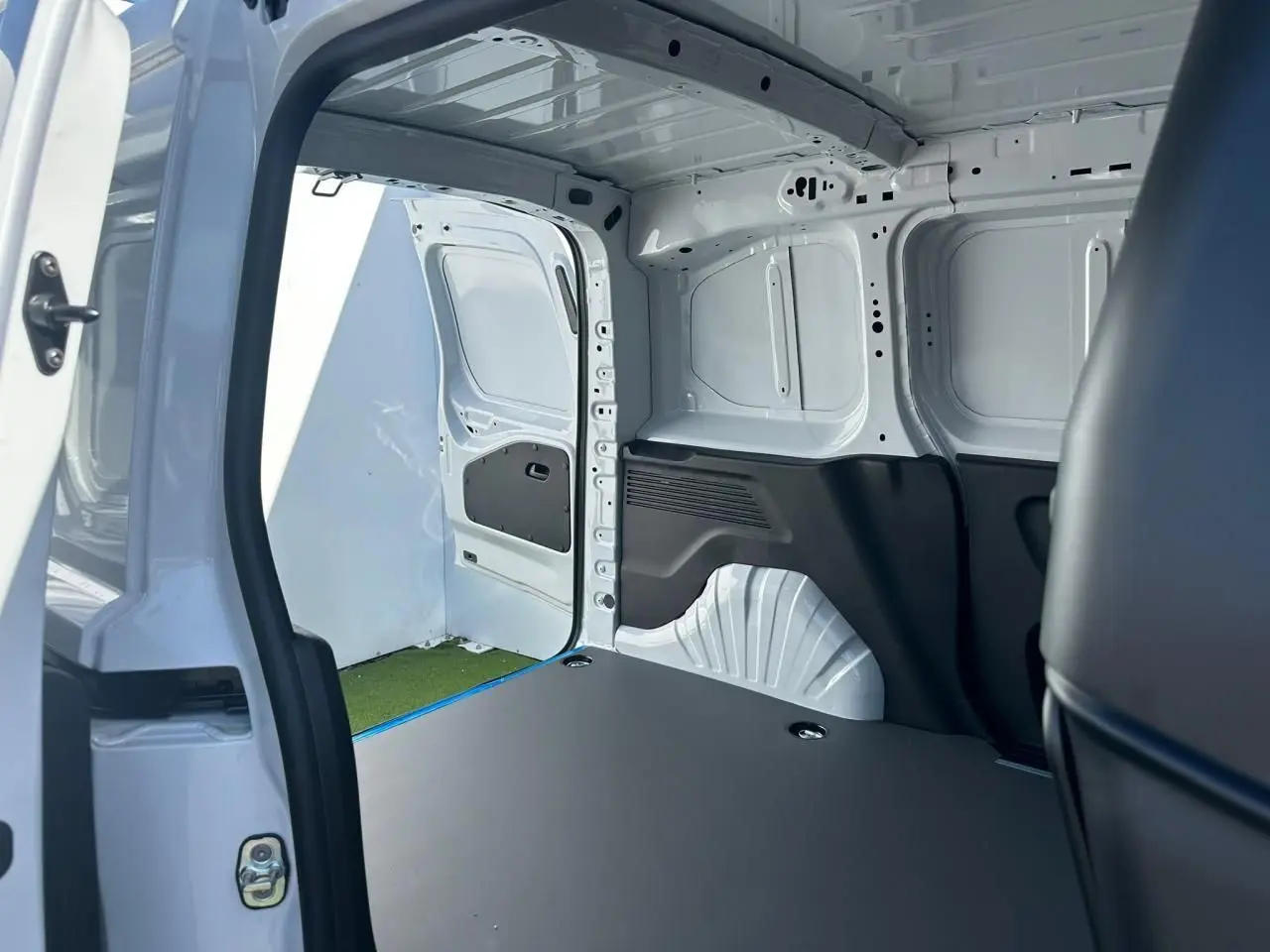 Vue intérieure de la zone de chargement du Citroën Berlingo blanc Icy, avec porte latérale droite ouverte et plancher plat.