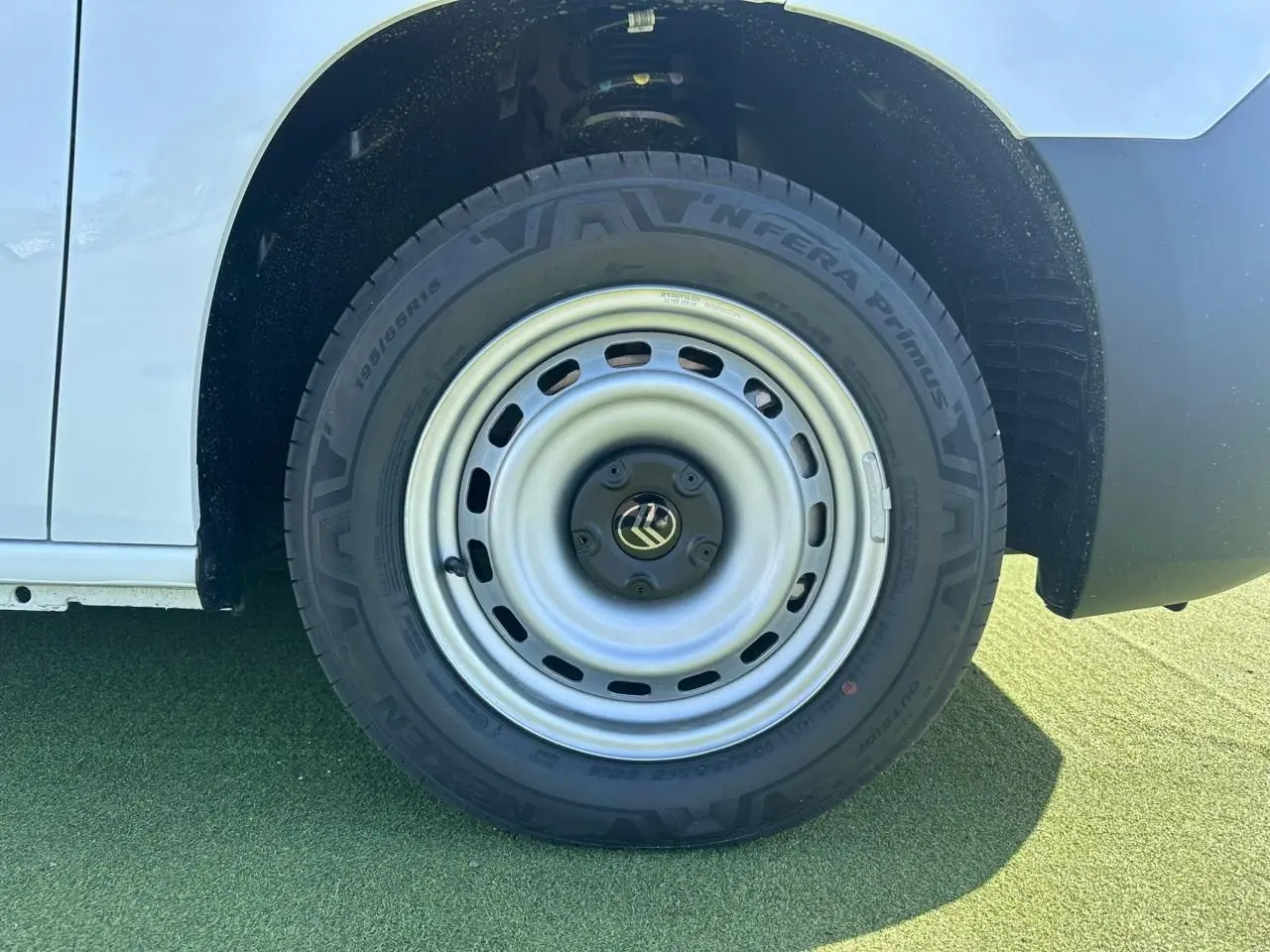 Gros plan sur la roue avant droite en jante tôle grise du Citroën Berlingo blanc Icy, partie basse de la carrosserie visible.