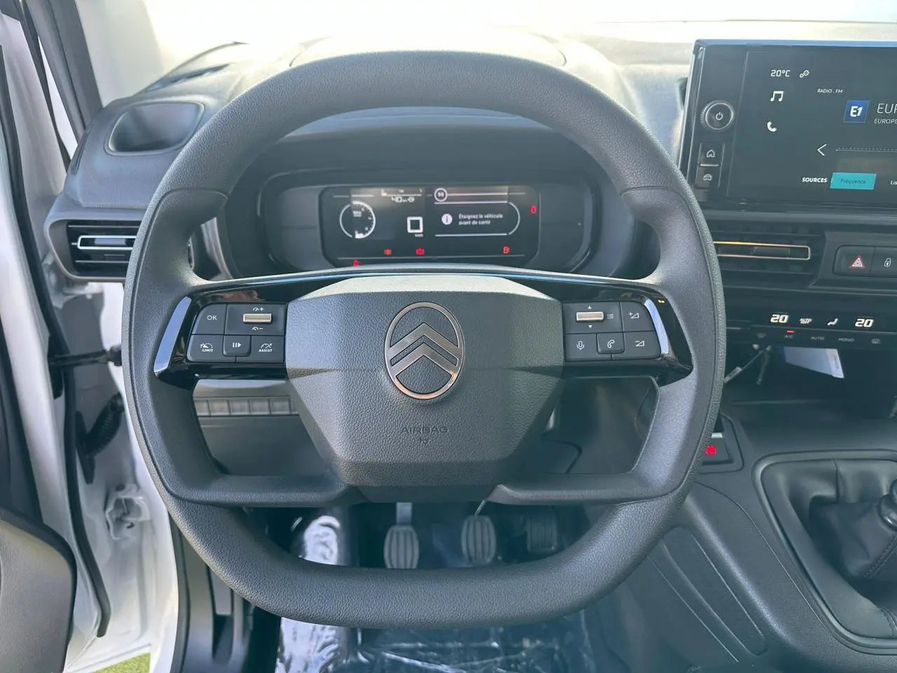 Poignée de porte noire brillante sur la porte avant gauche du Citroën Berlingo III blanc Icy, vue rapprochée en extérieur.