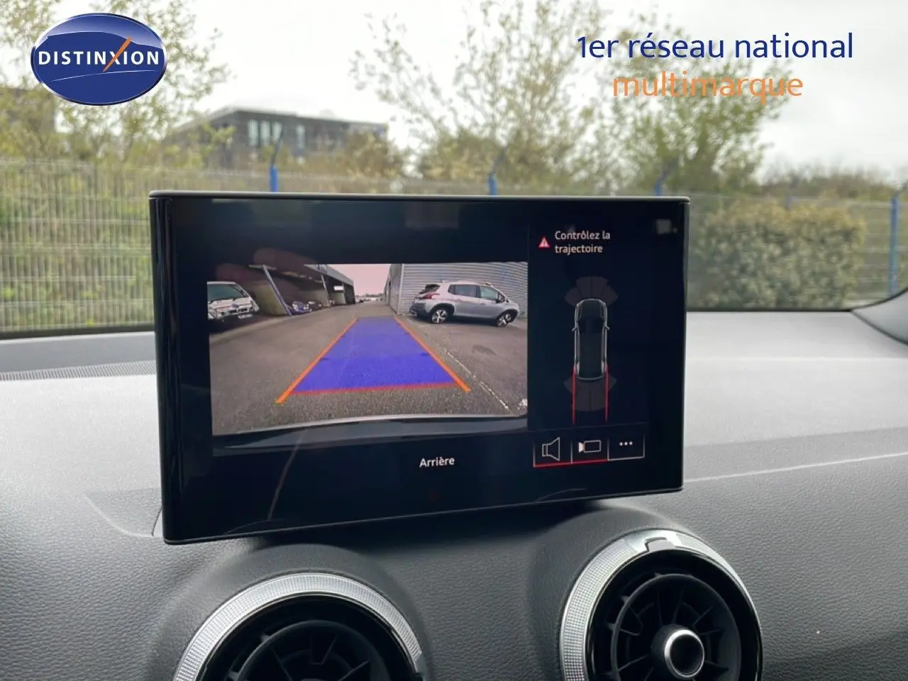 Écran central affichant la caméra de recul et l'aide au stationnement sur Audi Q2 noir mito metal, vue intérieure avant.