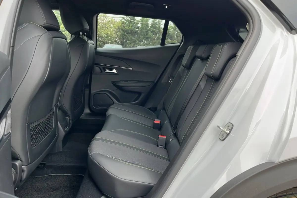 Vue latérale droite de l’habitacle arrière du Peugeot 2008 blanc, avec sièges en cuir noir et surpiqûres vertes.