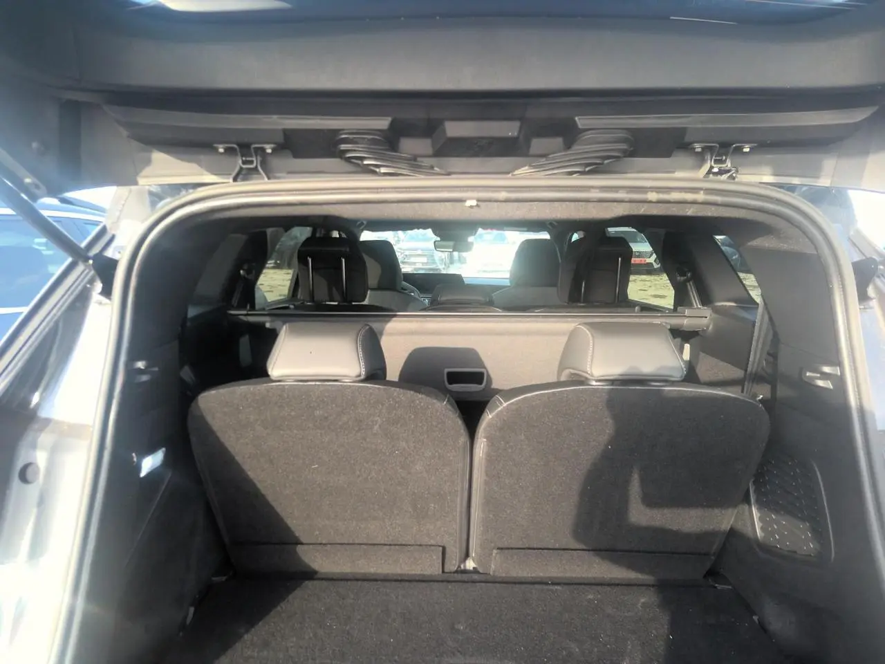 Vue arrière du coffre ouvert d’un Peugeot 5008 gris foncé, montrant les sièges arrière relevés et l’habitacle intérieur.