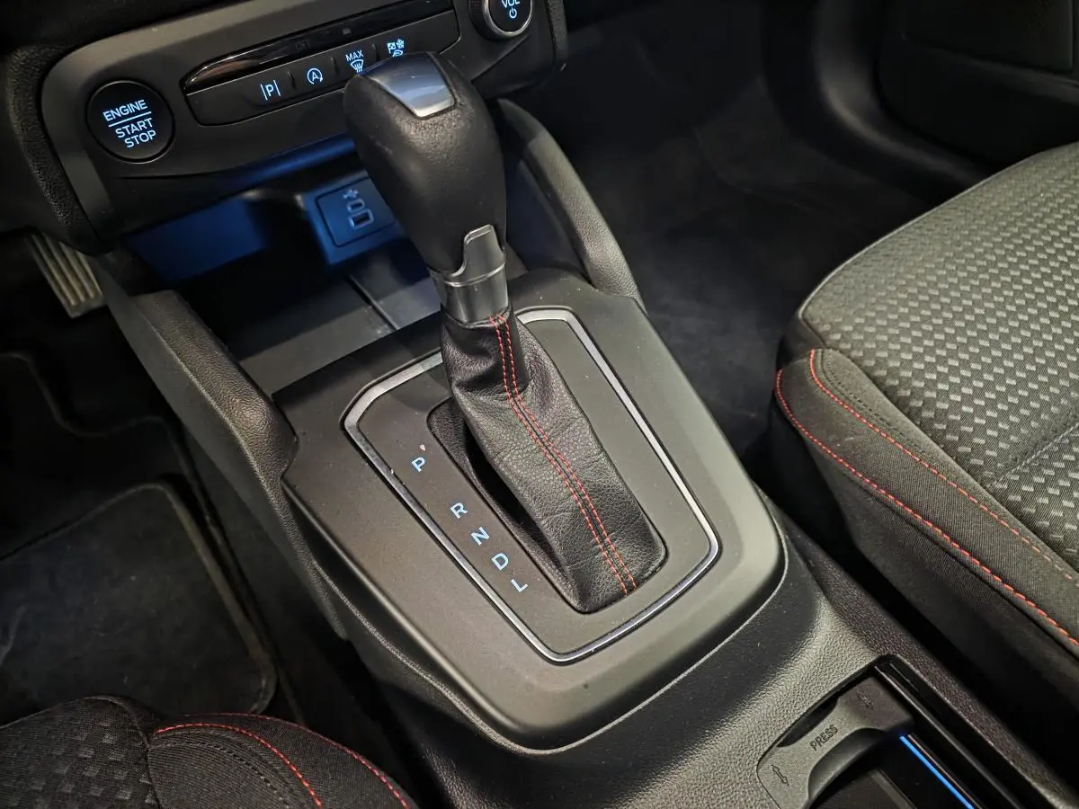 Gros plan sur le levier de vitesses automatique noir avec surpiqûres rouges dans l’habitacle de la Ford Focus ST Line 2024.