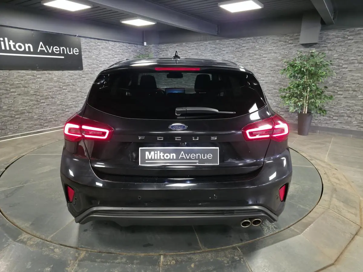 Vue arrière d'une Ford Focus noire 2024 avec feux LED allumés et double sortie d'échappement côté droit.