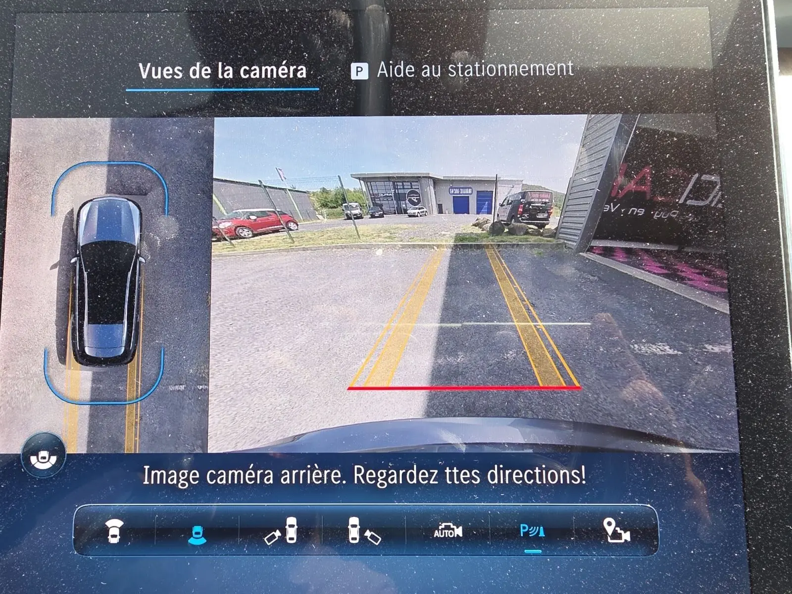 Affichage de la caméra 360° arrière d’un Mercedes Classe C Break gris foncé, avec lignes de guidage jaunes et rouges visibles.