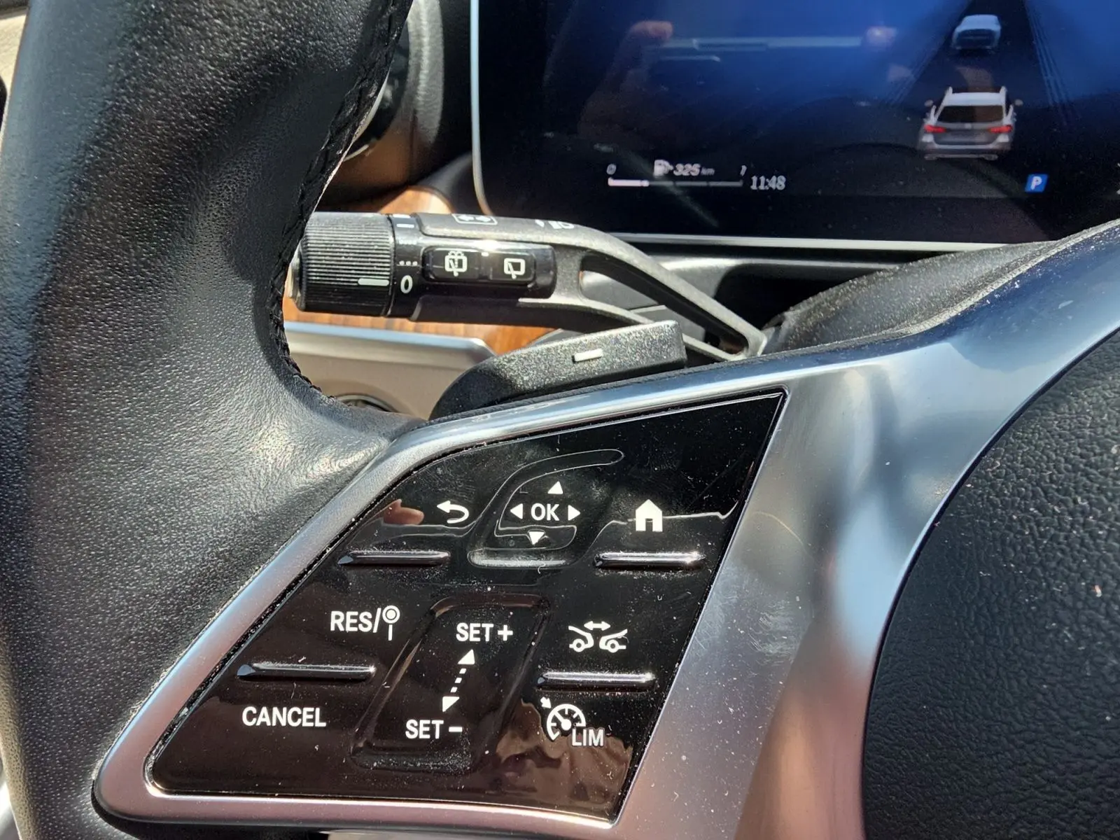 Gros plan sur les commandes au volant noir d’une Mercedes Classe C Break gris foncé, avec régulateur de vitesse adaptatif.