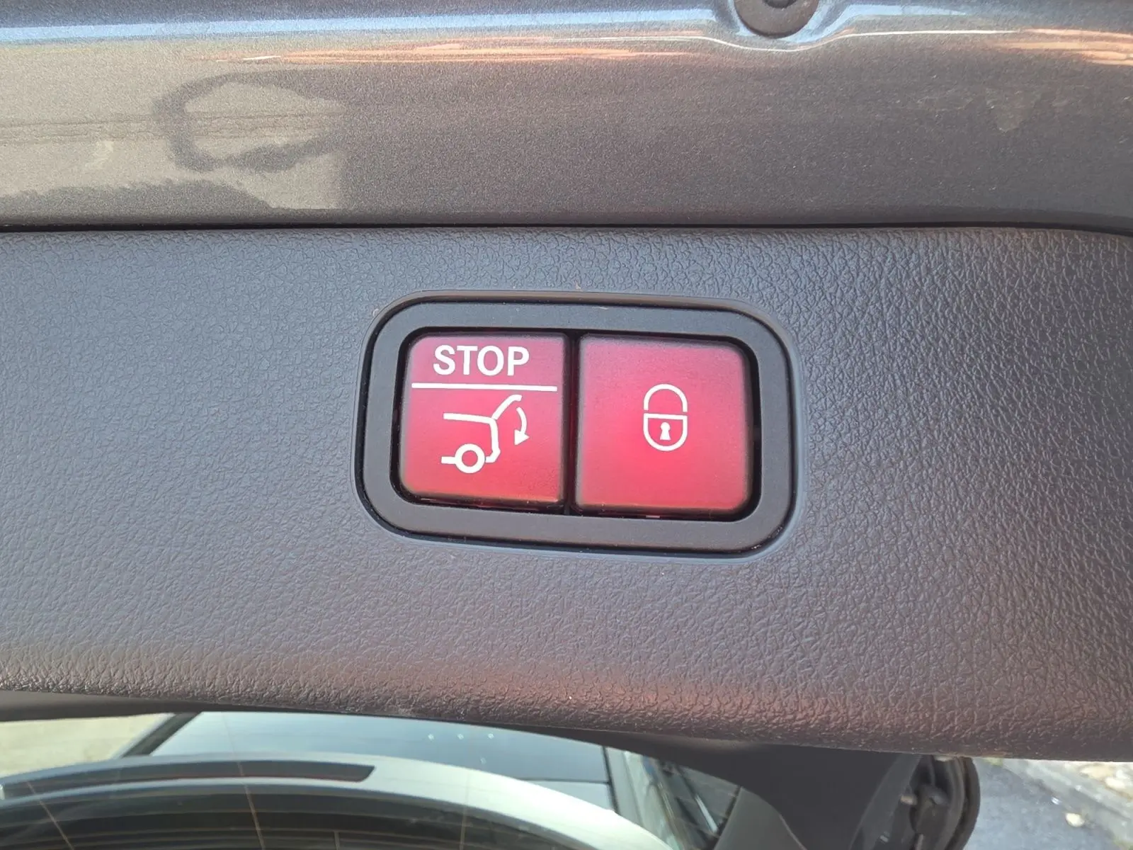 Gros plan sur les boutons rouges d'ouverture et verrouillage du hayon électrique d'un Mercedes Classe C Break gris foncé.