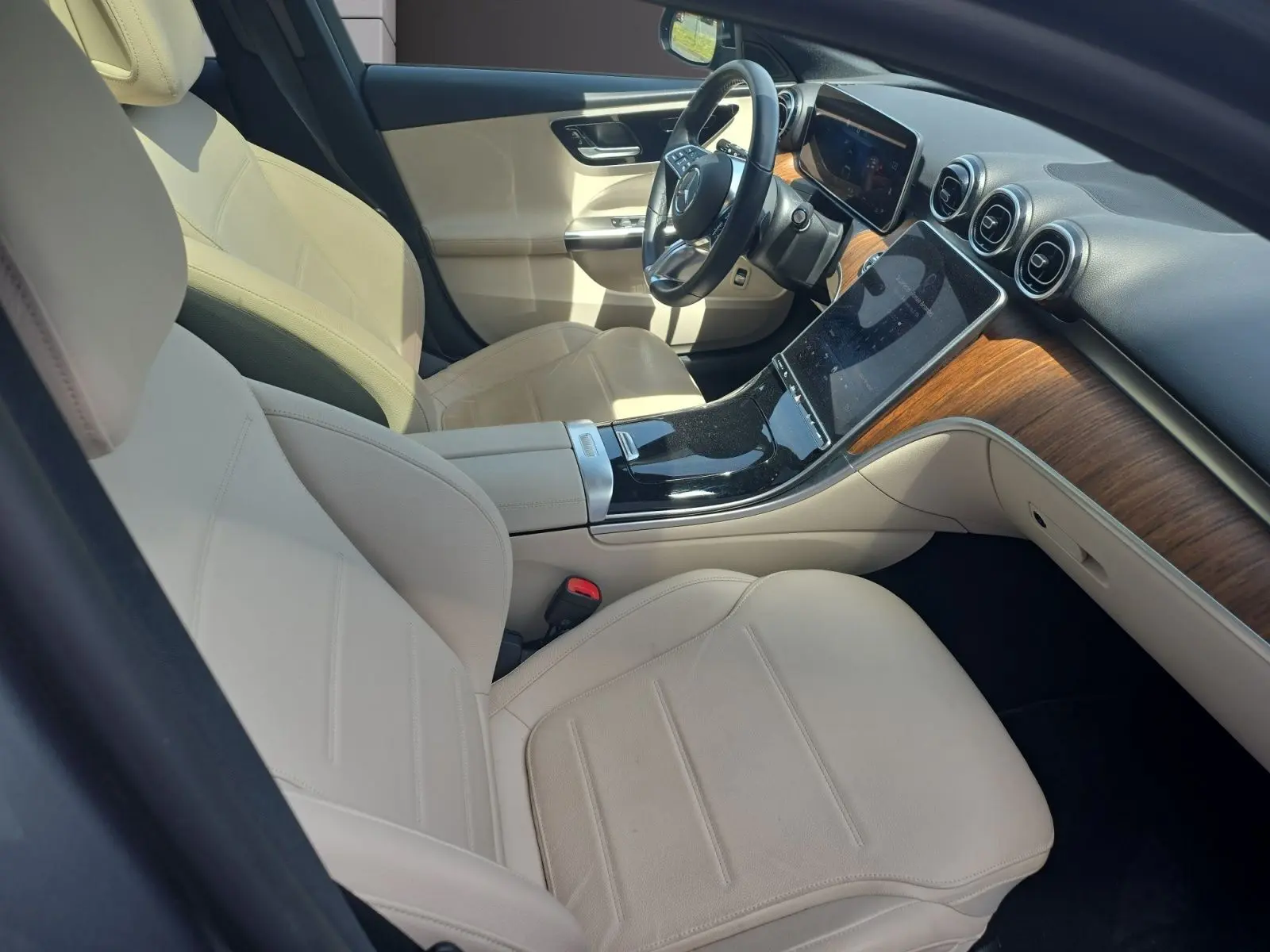 Vue intérieure côté conducteur de la Mercedes Classe C Break 220 D 4MATIC avec sellerie cuir beige et tableau de bord bois.