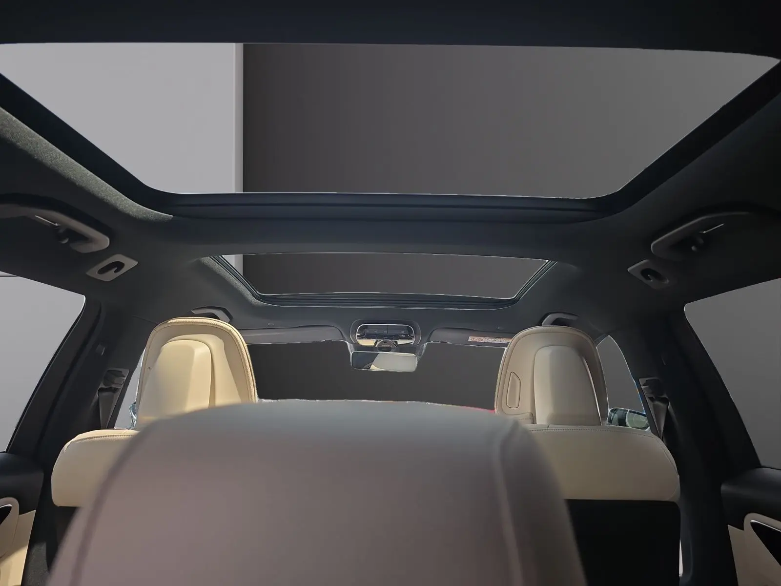 Vue intérieure arrière du break Mercedes Classe C gris foncé, avec toit ouvrant panoramique et sièges cuir beige.