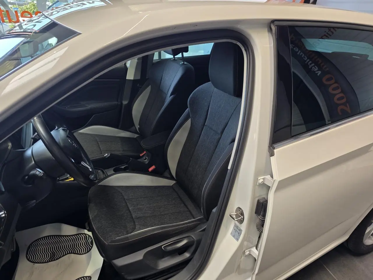 Vue intérieure côté conducteur d'une Skoda Scala blanche 2020, sièges tissu Ambition gris foncé avec surpiqûres claires.