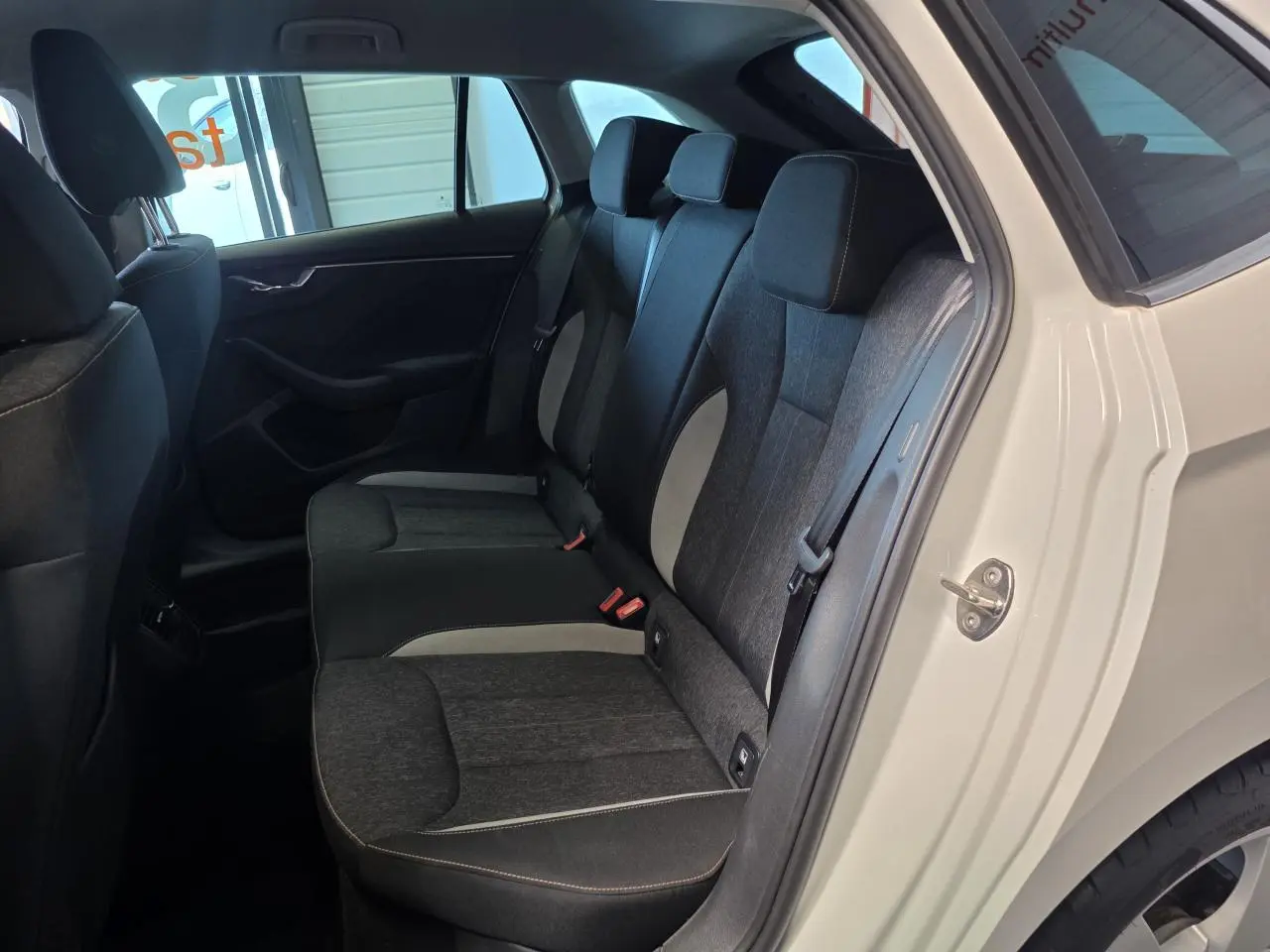 Vue intérieure côté arrière droit de la Skoda Scala blanche 2020, montrant la banquette arrière en tissu bicolore gris et noir.
