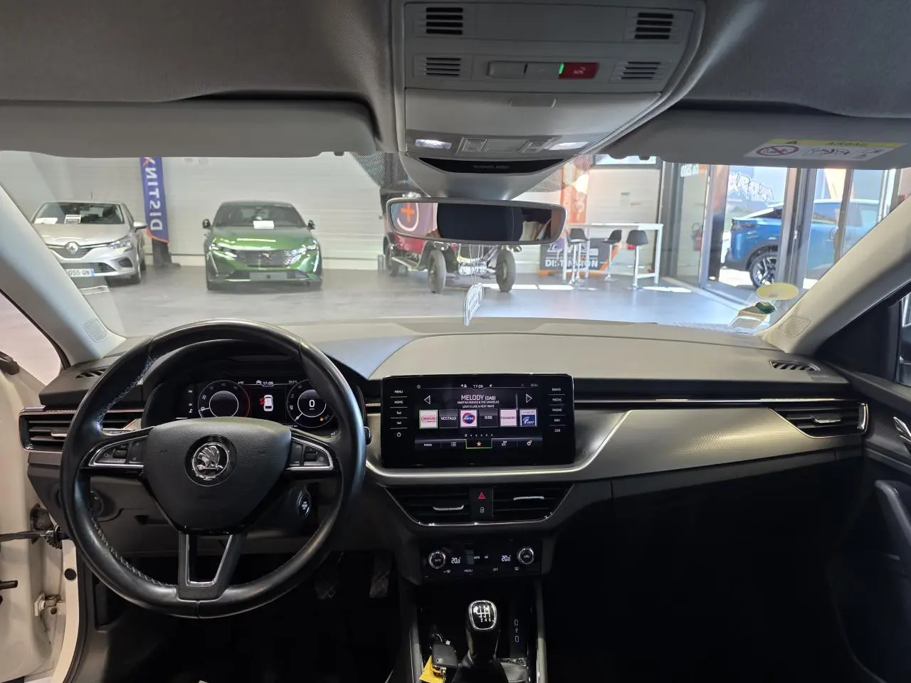Vue intérieure avant du tableau de bord noir et écran tactile central d'une Skoda Scala blanche de 2020 avec boîte manuelle.