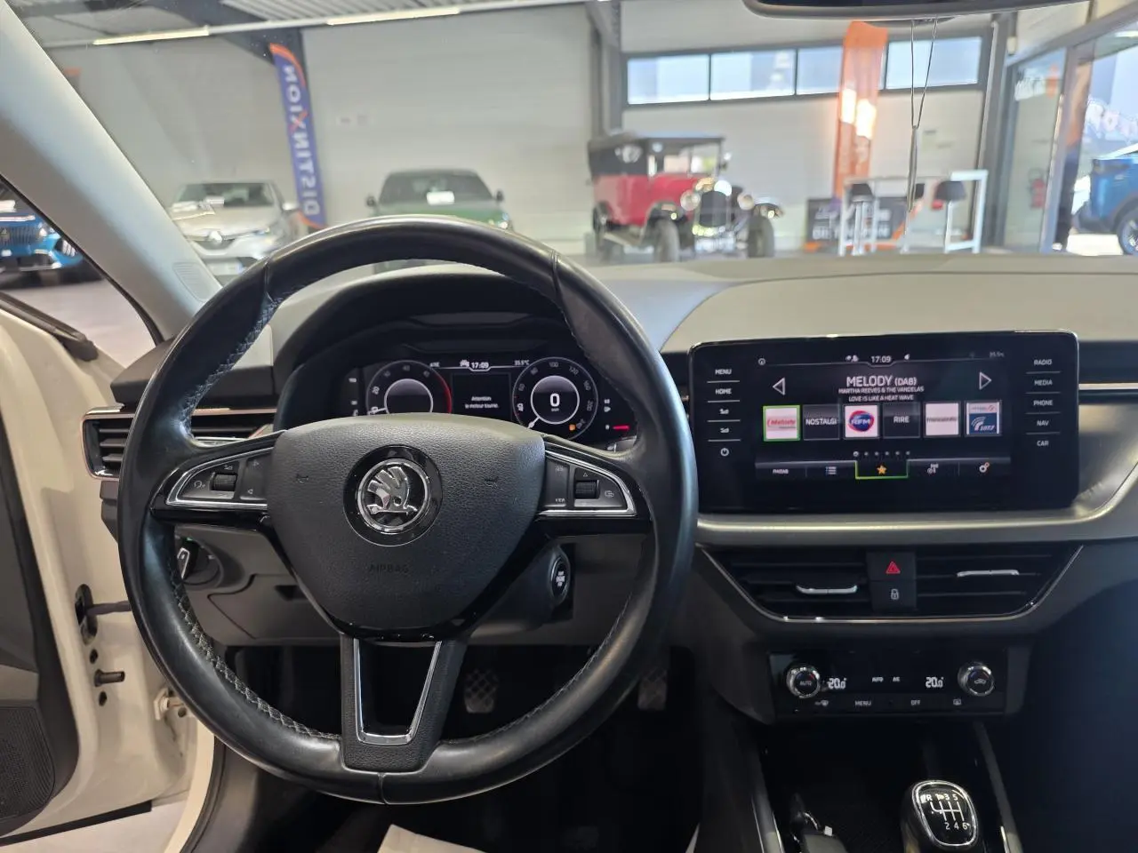 Vue intérieure centrée sur le volant cuir et le tableau de bord digital de la Skoda Scala blanche de 2020.