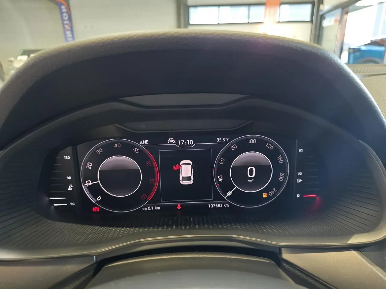 Tableau de bord numérique du Skoda Scala blanc, affichant vitesse à 0 km/h et porte ouverte, vue de face rapprochée.