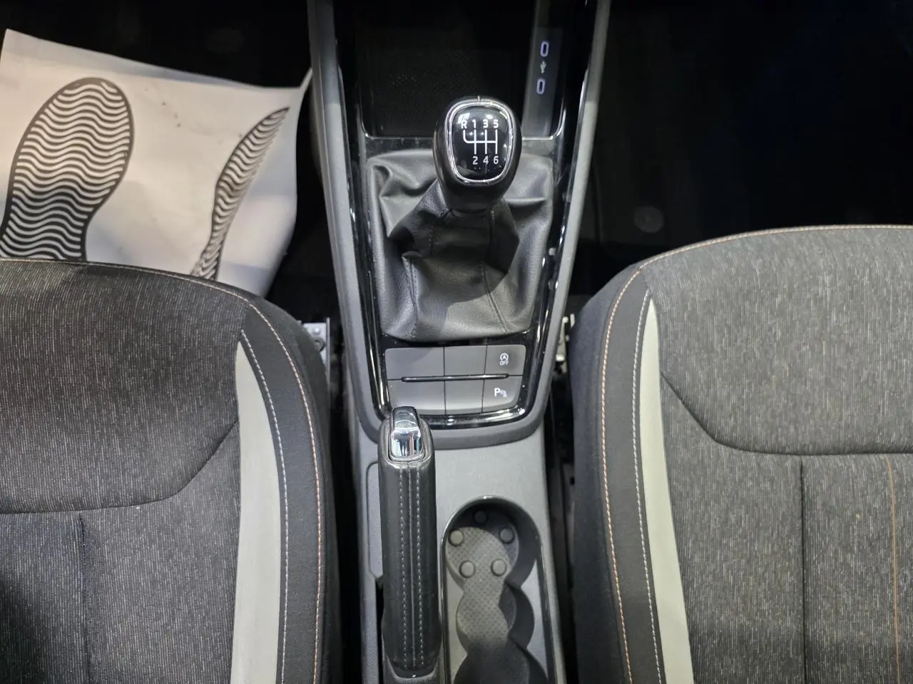 Vue plongeante sur la console centrale d’une Skoda Scala blanche, avec levier de vitesses manuel et frein à main en cuir.