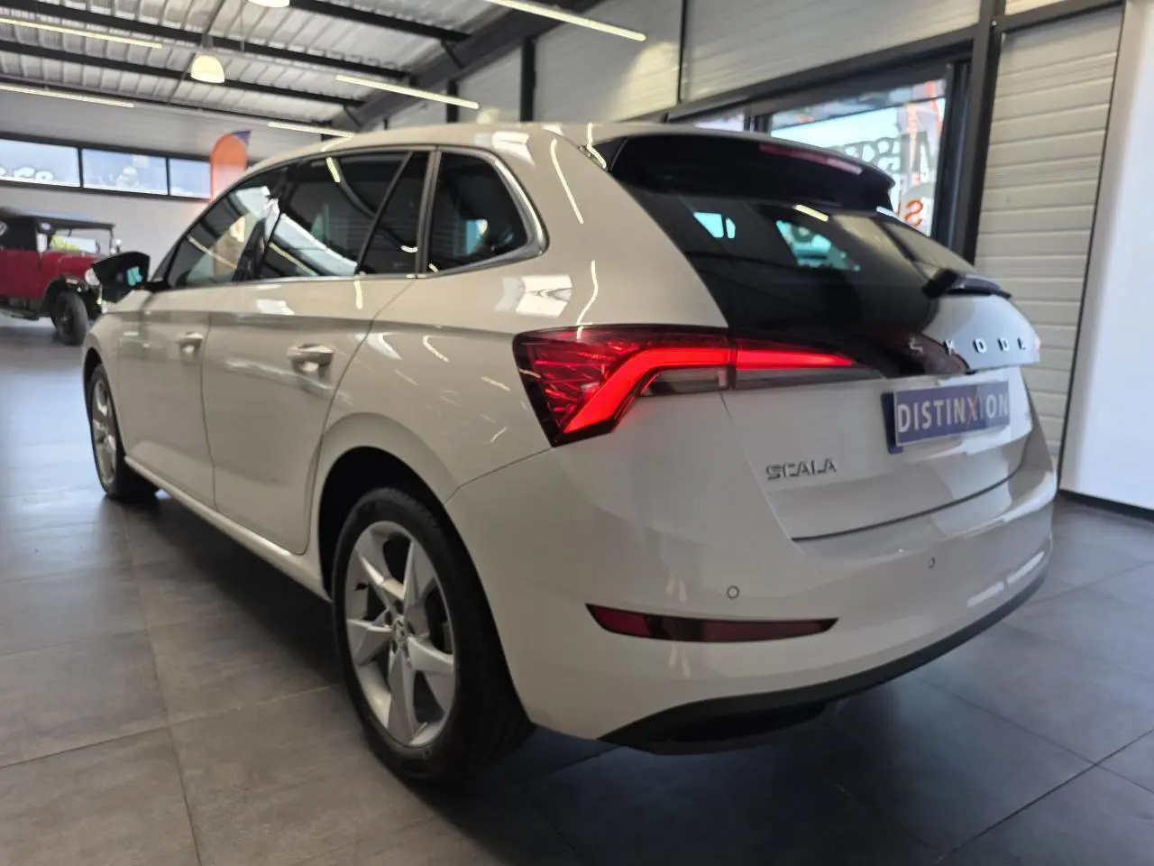 Vue 3/4 arrière droite d'une Skoda Scala blanche avec feux arrière LED et jantes alliage en showroom.