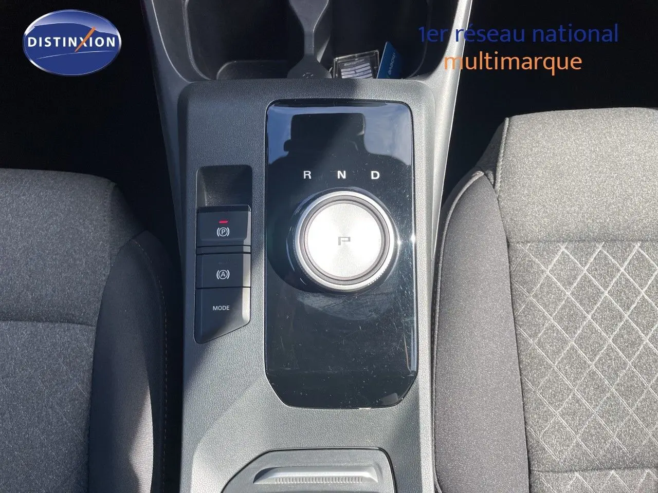 Vue plongeante sur la console centrale de la MG3 2024 Pebble Black, avec molette de boîte auto et sièges tissu gris.