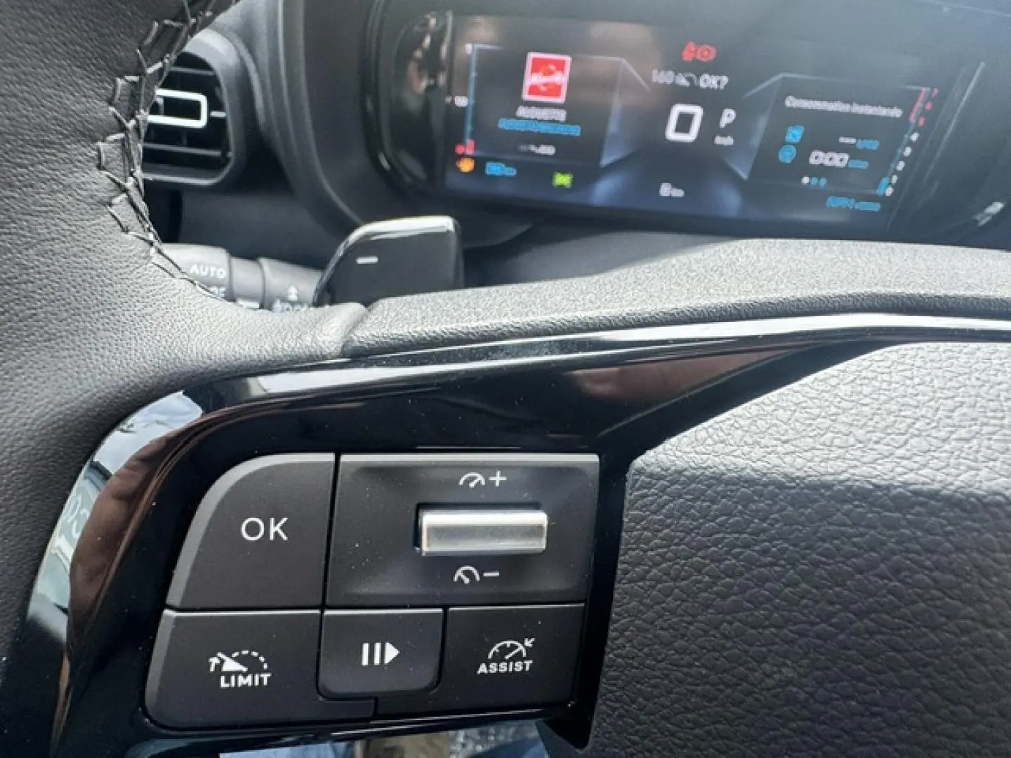 Gros plan sur les commandes au volant cuir noir du Citroën Berlingo 2026, avec affichage numérique en arrière-plan.