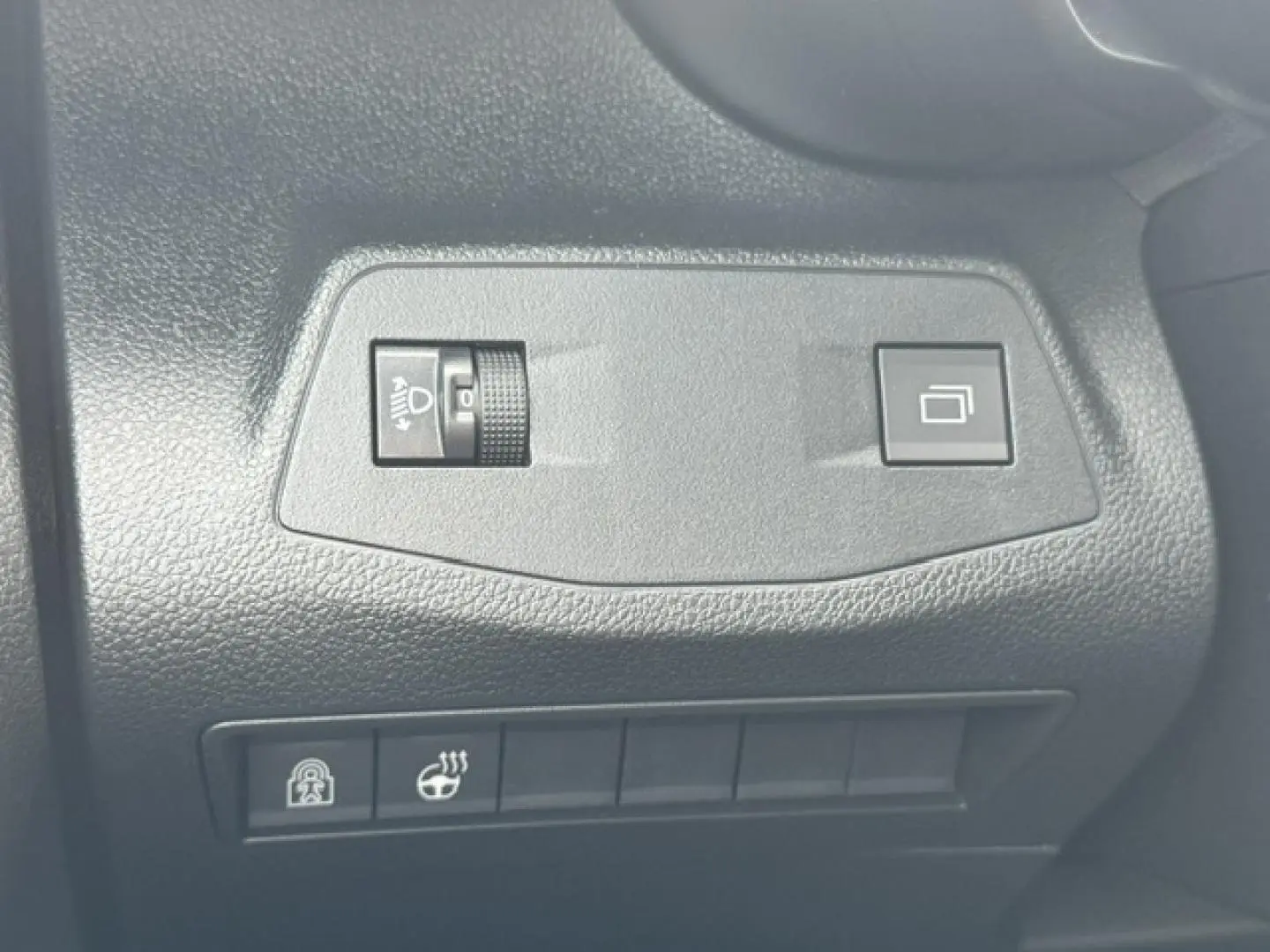 Détail des commandes de réglage des phares et verrouillage dans l'habitacle d'un Citroën Berlingo gris acier.