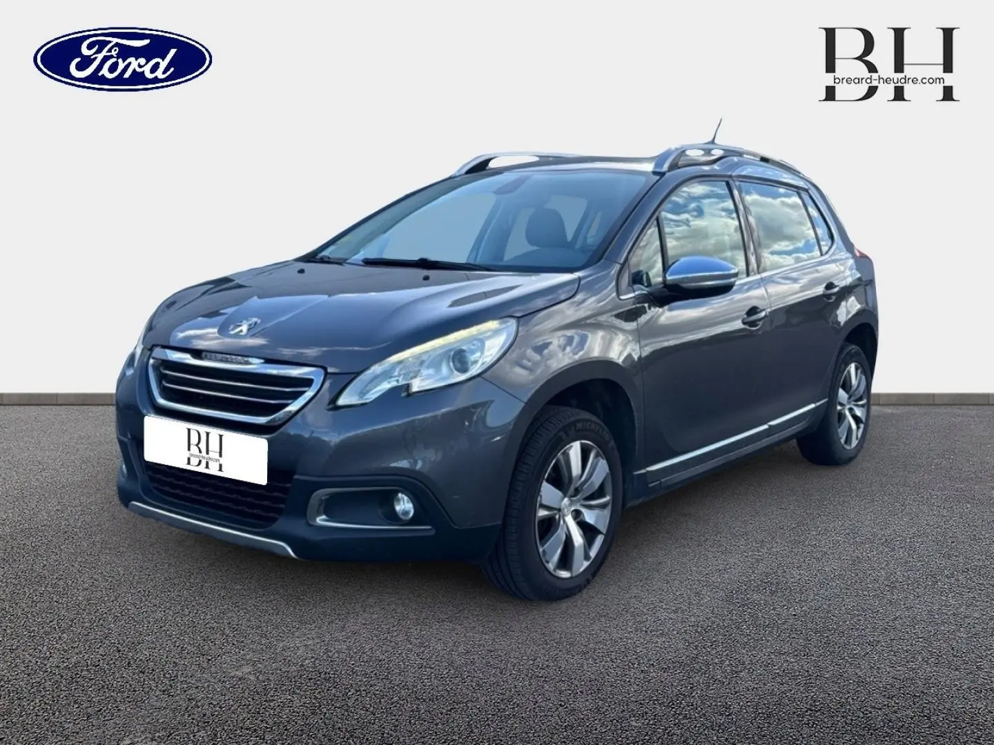 Peugeot 2008 Spirit Grey vue 3/4 avant droit, avec barres de toit et jantes alliage visibles.