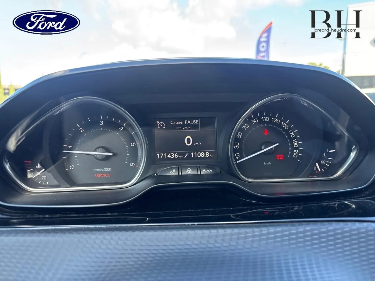 Vue rapprochée du tableau de bord d'un Peugeot 2008 gris, affichant le compteur et l'ordinateur de bord.