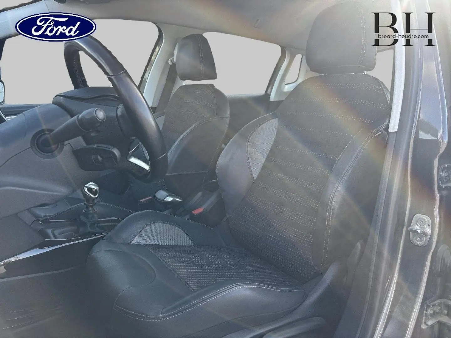 Vue intérieure côté conducteur du Peugeot 2008 1.6 BlueHDi 120ch Allure S&S 2015, sièges noirs et volant cuir multifonction.