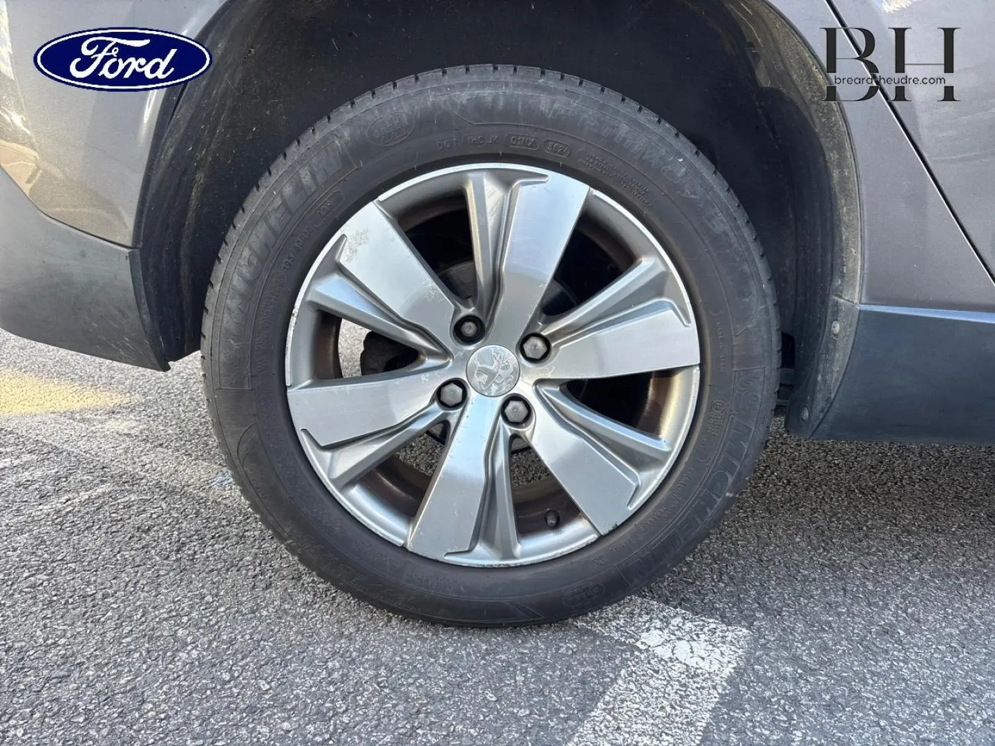 Gros plan sur la roue avant droite d’un Peugeot 2008 gris Spirit avec jante alliage à 5 branches doubles.