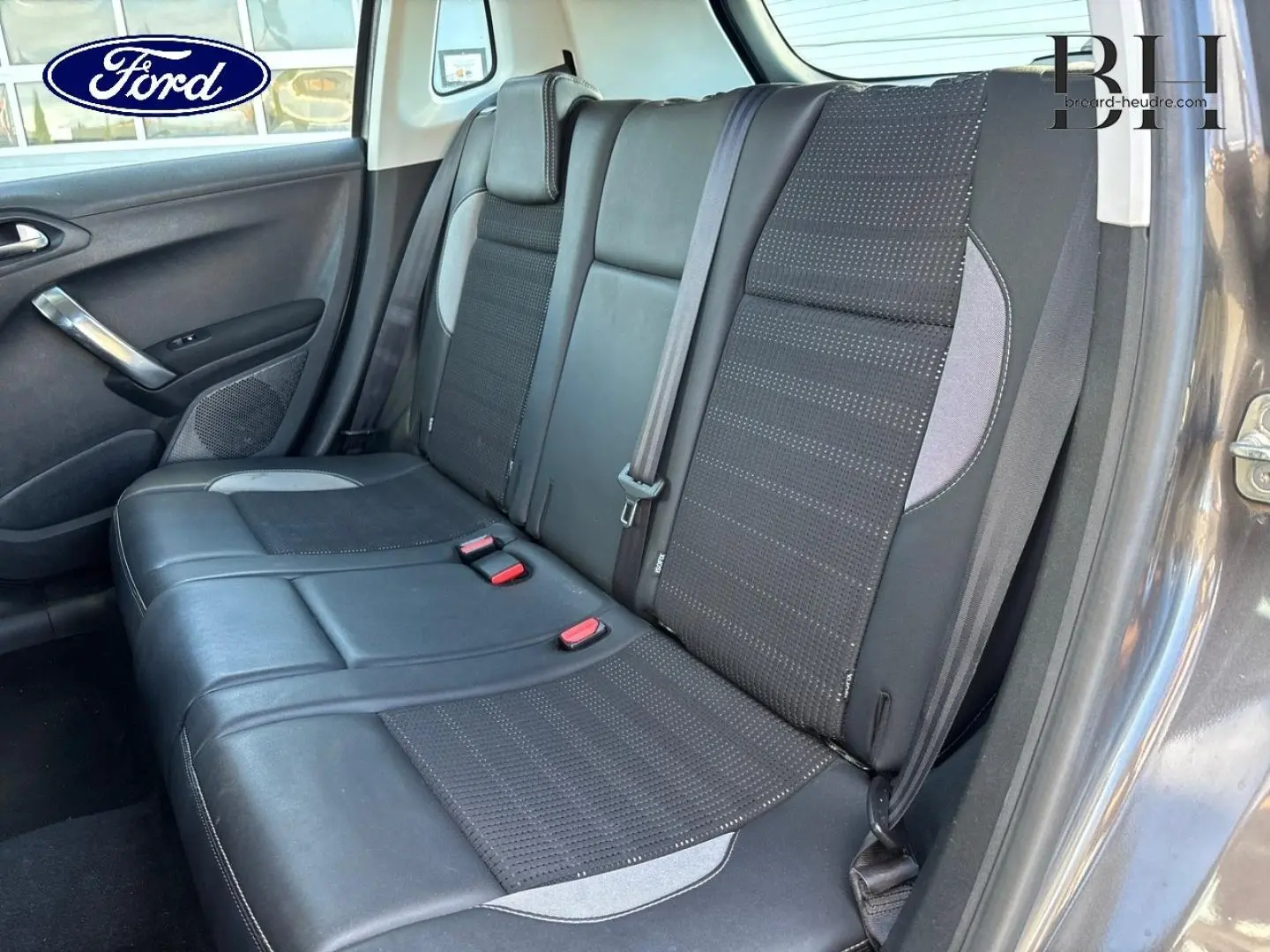Vue intérieure montrant la banquette arrière en cuir et tissu noir du Peugeot 2008 Spirit Grey, côté droit ouvert.