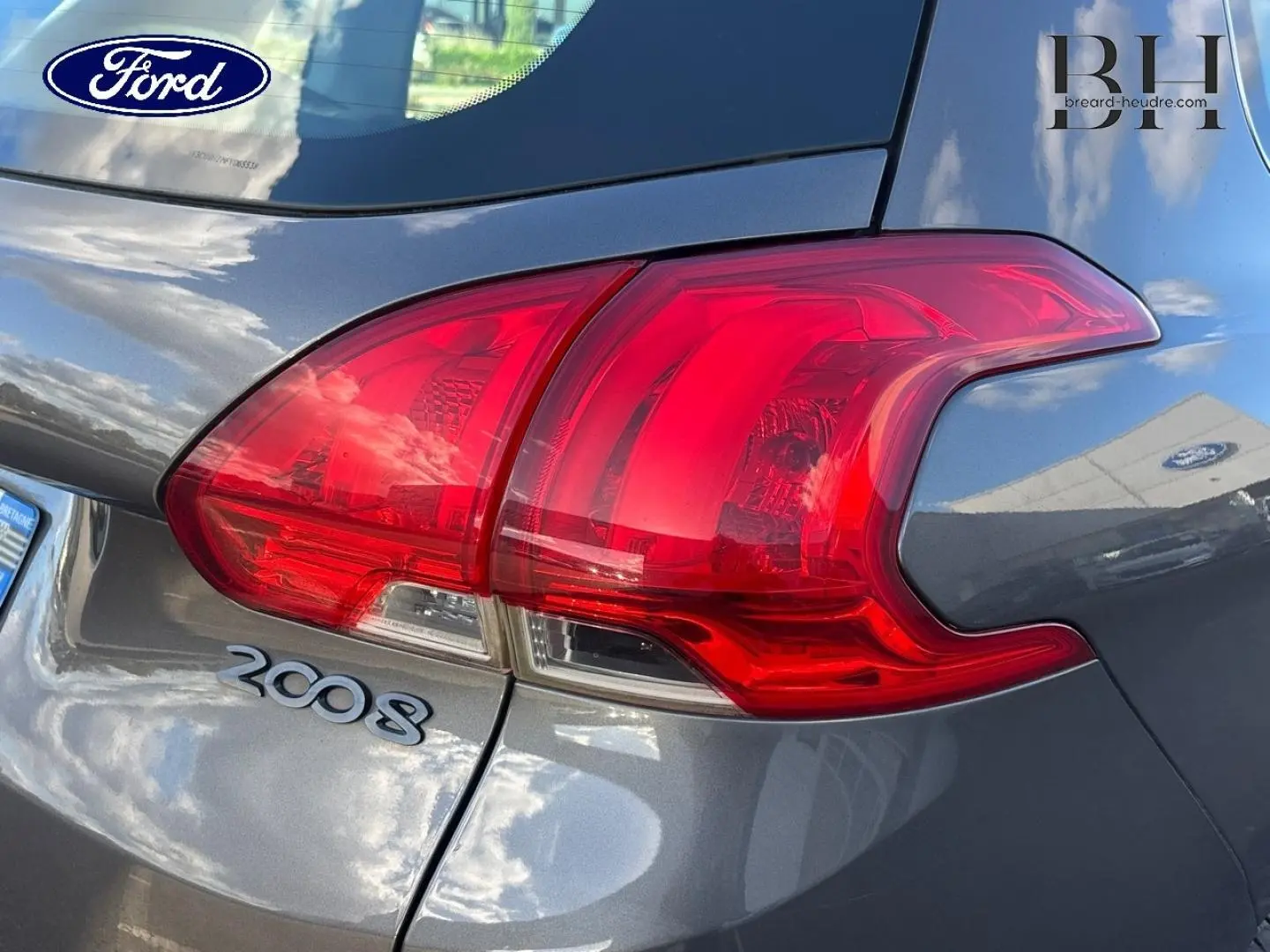 Gros plan sur le feu arrière droit d’un Peugeot 2008 gris Spirit avec logo et badge visibles.