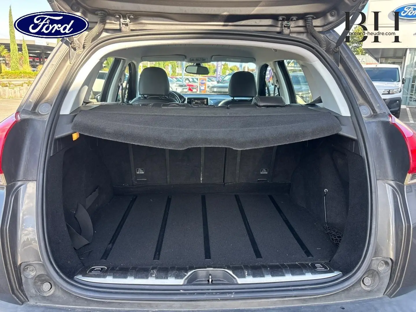 Coffre ouvert vu de l'arrière d'un Peugeot 2008 Spirit Grey avec cache-bagages et banquette arrière visible.