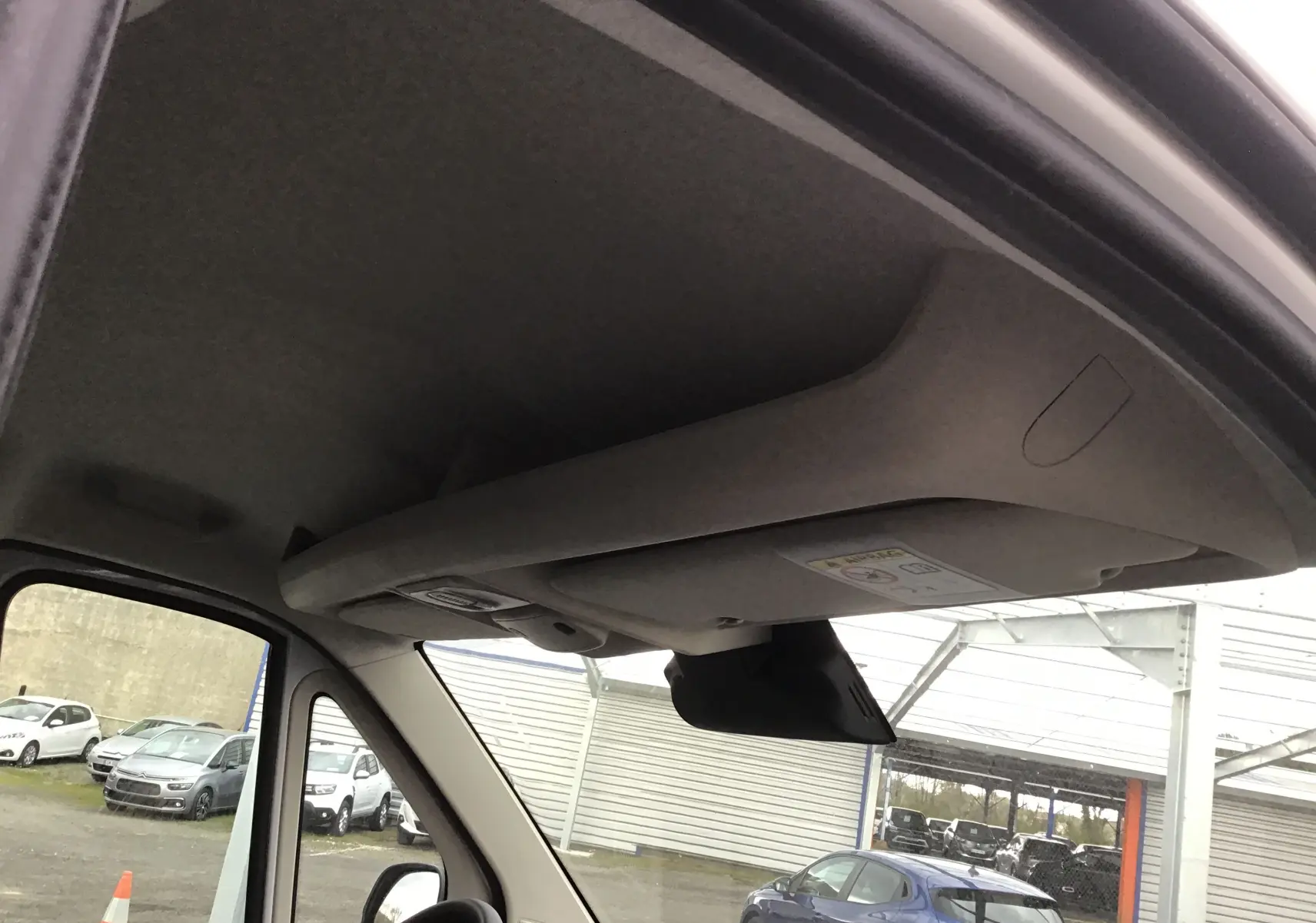 Vue intérieure du plafond et pare-soleil du Peugeot Boxer Fourgon blanc, avec rétroviseur et partie du pare-brise visibles.