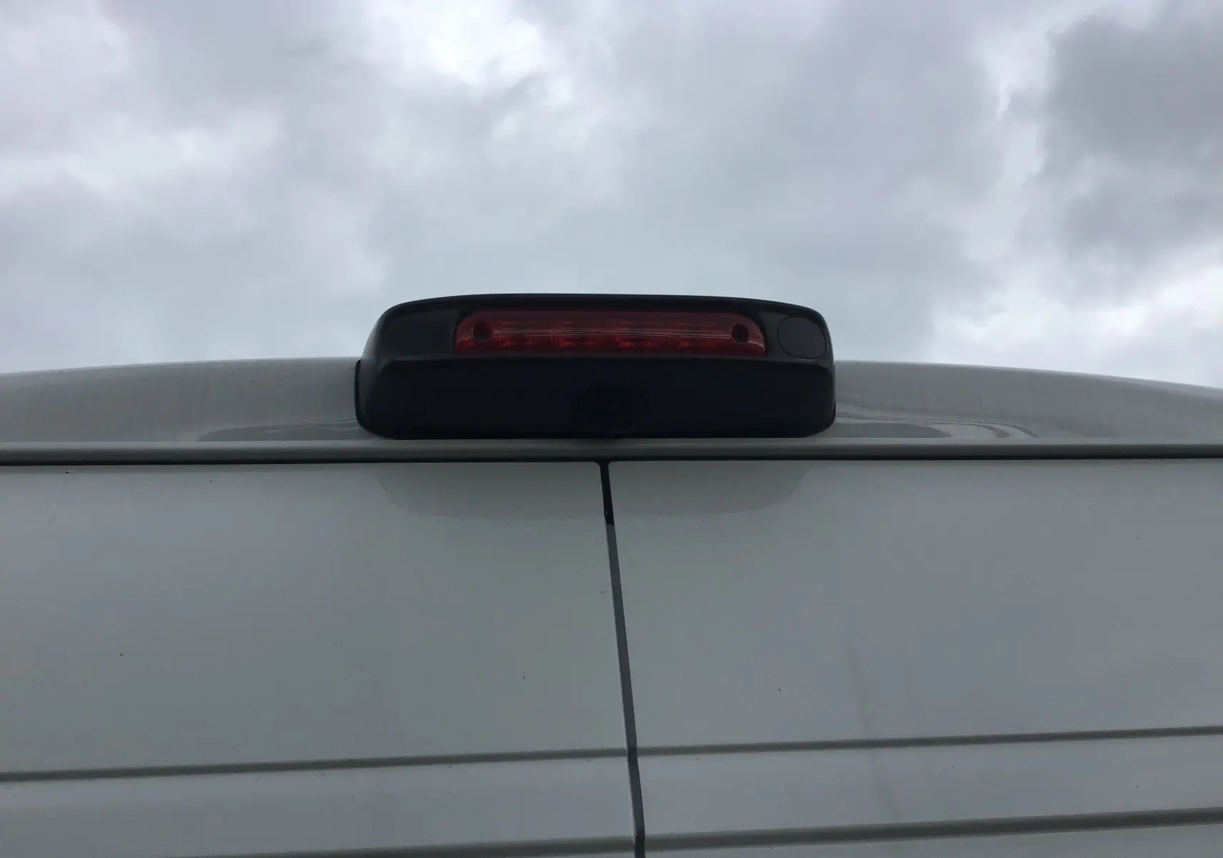 Gros plan sur la caméra de recul et le feu stop supérieur du Peugeot Boxer Fourgon blanc, vue arrière haute.