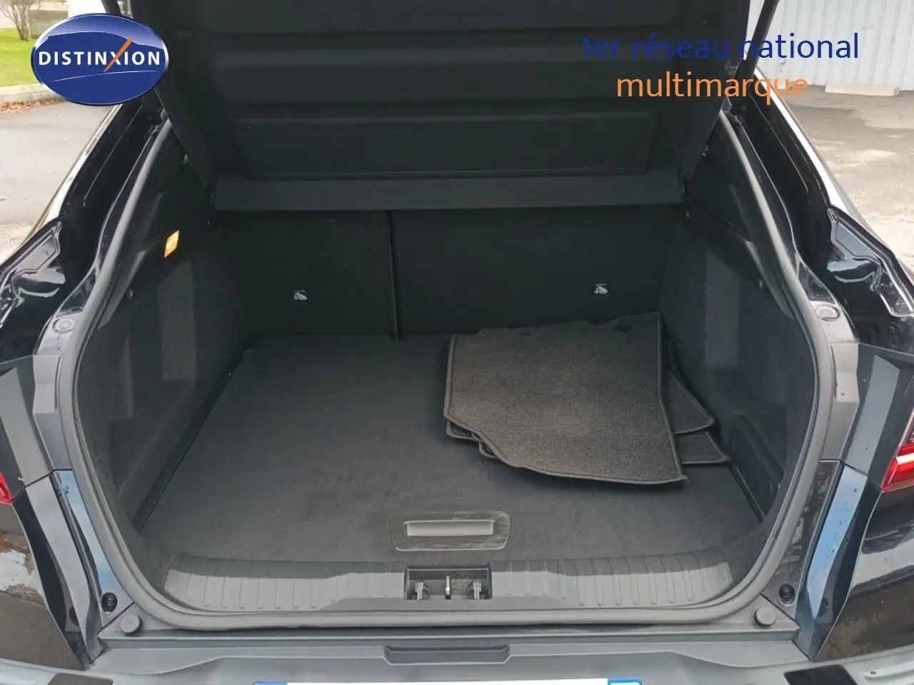 Coffre ouvert vu de l'arrière d'un Renault Arkana noir 2021, avec tapis de sol gris à l'intérieur.