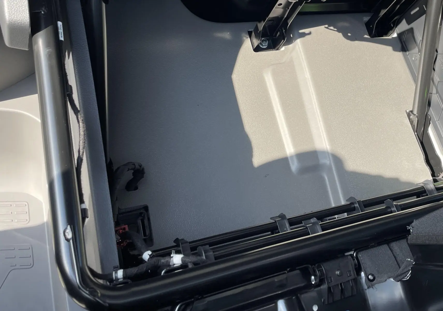 Vue plongeante sur le plancher gris clair du Volkswagen Crafter Van 2025, montrant la cloison et câblage noir.
