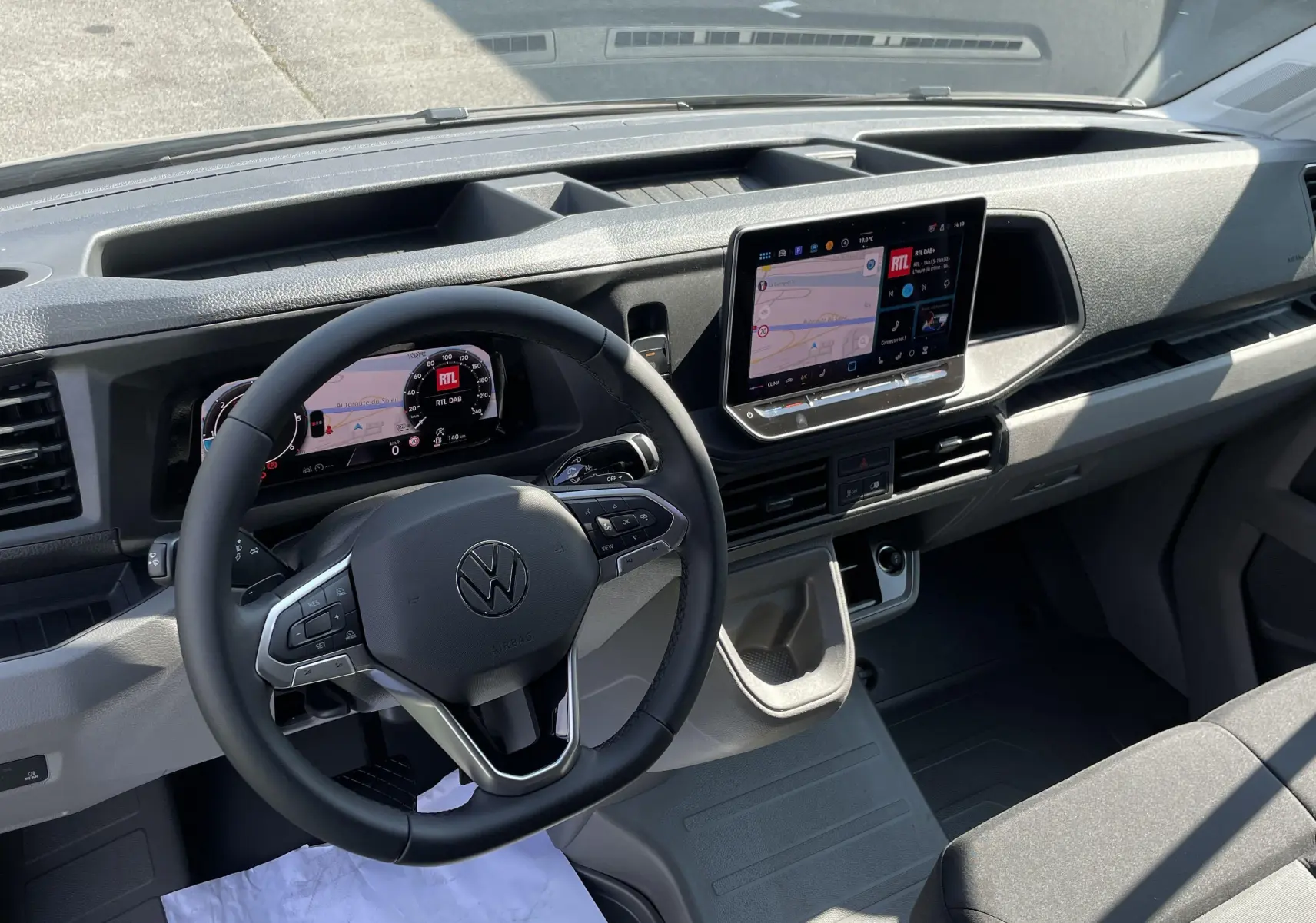 Vue intérieure du tableau de bord du Volkswagen Crafter gris Indium, avec écran tactile et volant multifonction.