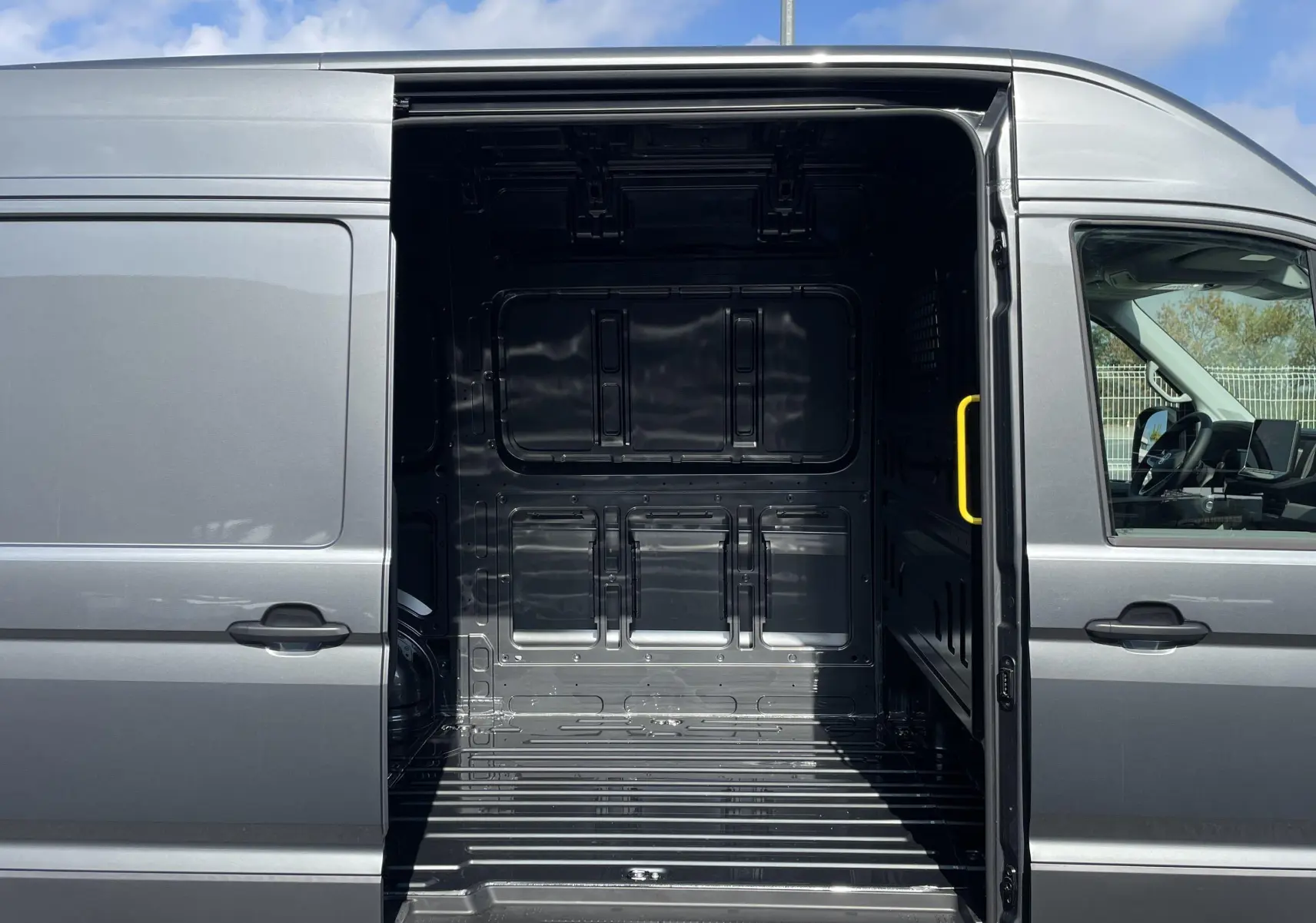 Vue latérale droite du Volkswagen Crafter gris Indium avec porte coulissante ouverte montrant l'espace de chargement vide