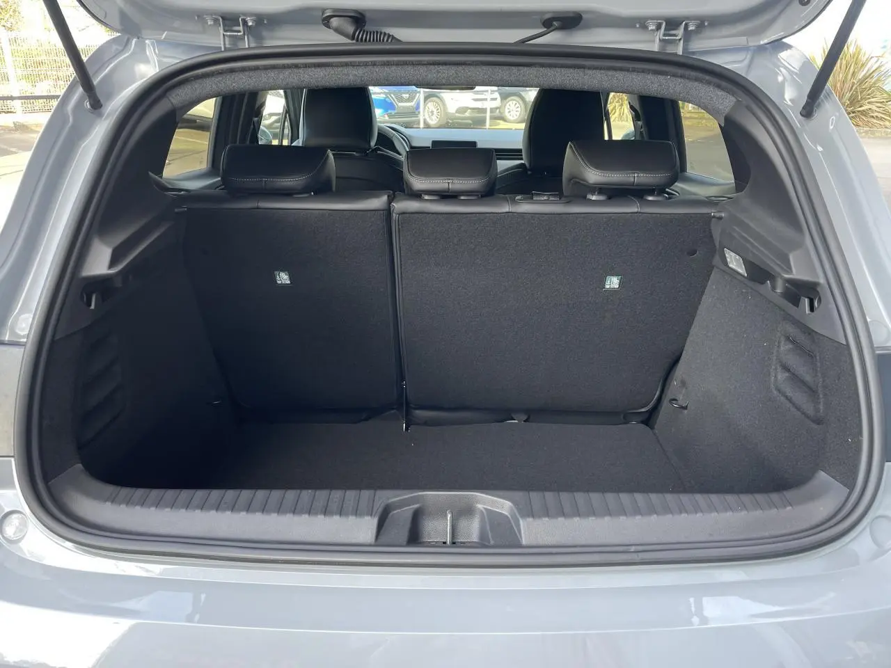 Coffre ouvert vu de l'arrière d'une Renault Clio Gris Rafale, montrant l'espace de chargement et les sièges arrière.