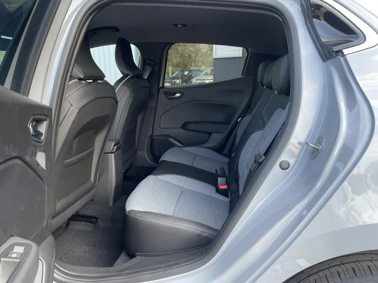 Vue côté droit arrière de l'habitacle d'une Renault Clio Gris Rafale, montrant les sièges arrière bi-matière gris et noir.