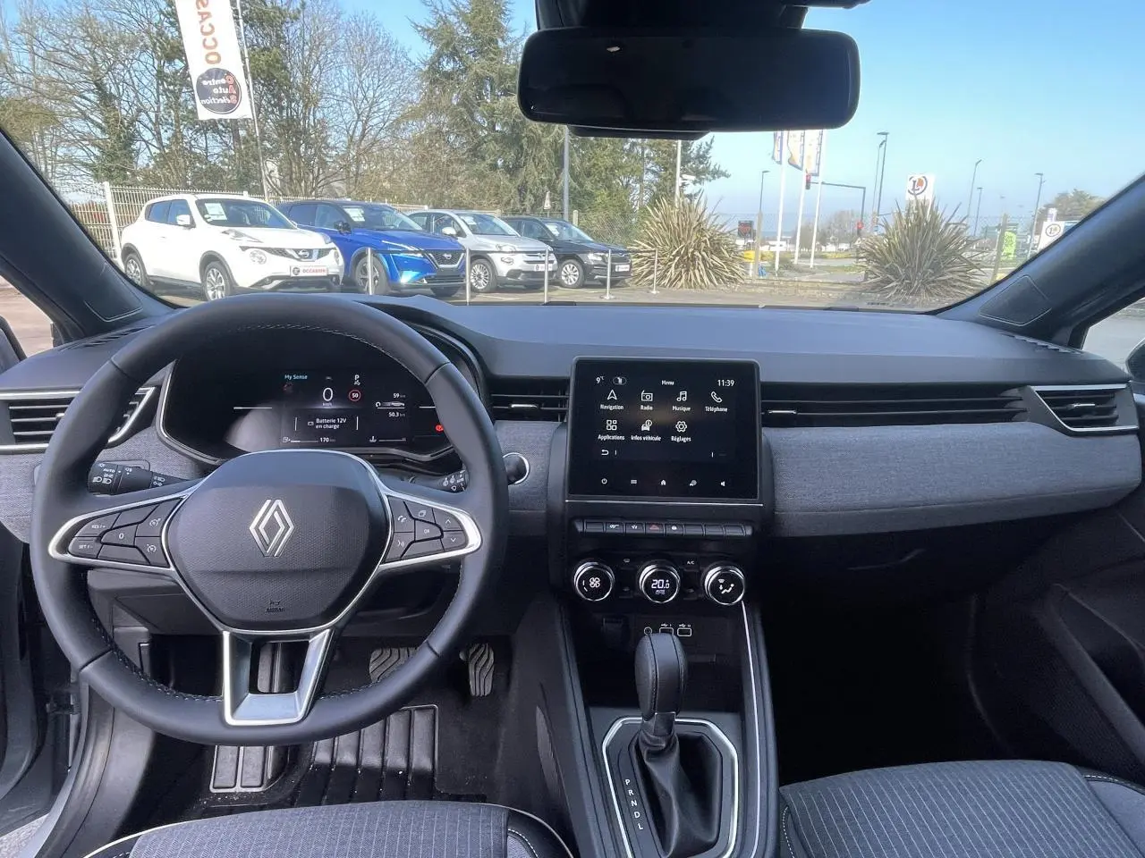 Vue intérieure du tableau de bord et volant de la Renault Clio 2025 avec écran tactile et sellerie gris foncé.