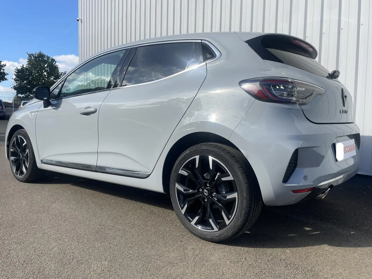 Vue 3/4 arrière droite d'une Renault Clio Gris Rafale avec jantes alliage diamantées 17 pouces et entourage aluminium des vitres.