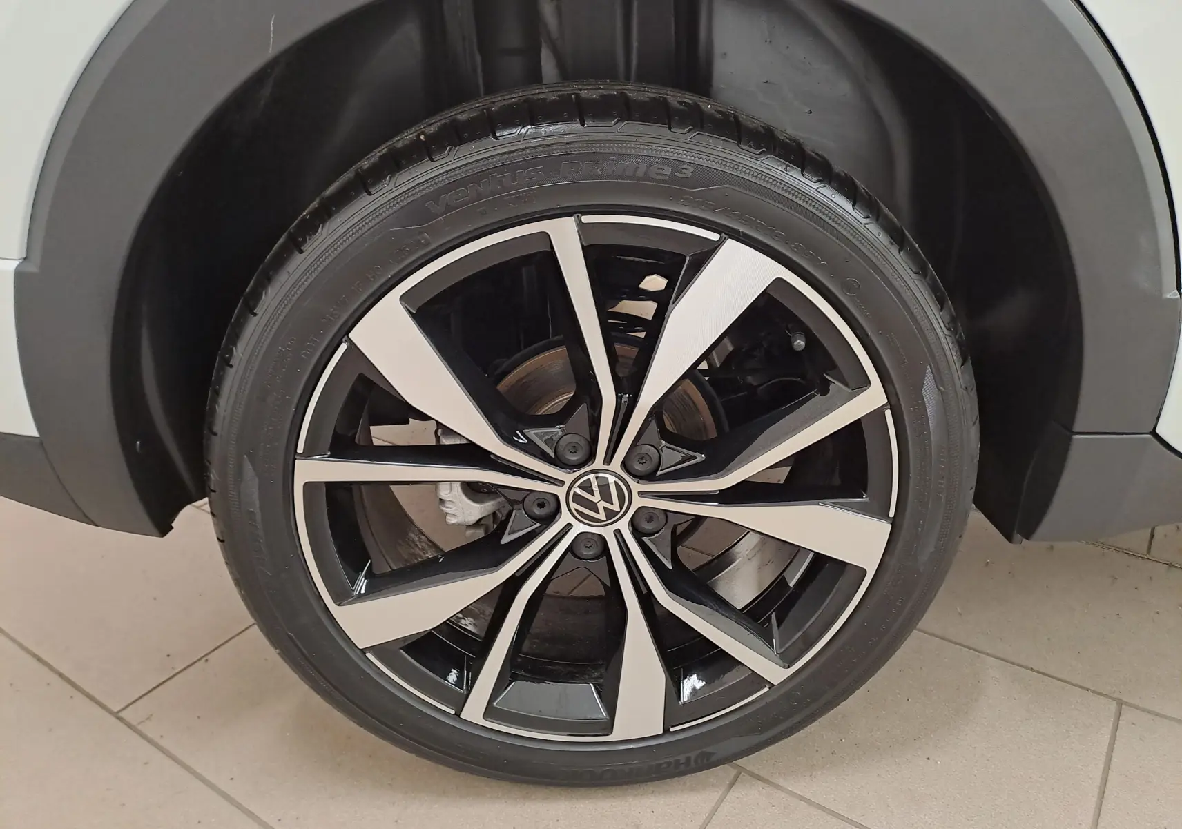 Gros plan sur la jante alliage bicolore noire et argent du Volkswagen T-Cross blanc Pur 2025 version R-Line.